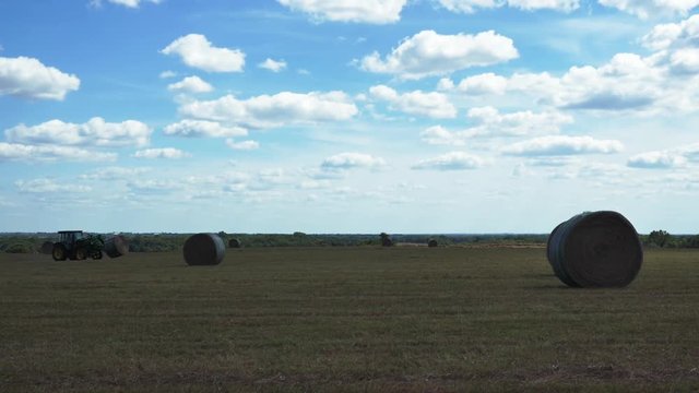 Tractor carries hay bale in field