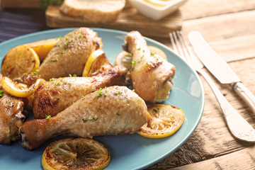 Delicious chicken legs with lemon on plate