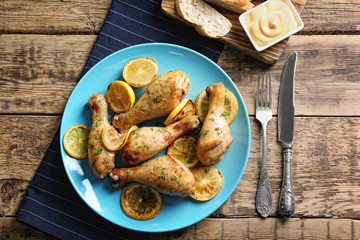 Delicious chicken legs with lemon on wooden table
