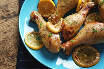 Delicious chicken legs with lemon on plate