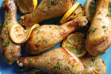 Delicious chicken legs with lemon on plate, closeup