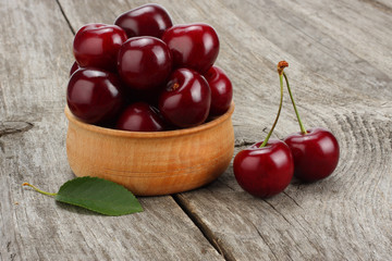 cherries in bowl on old wooden background
