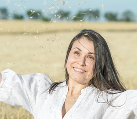 Pretty female enjoying a good harvest in wheat field at warm sunner day