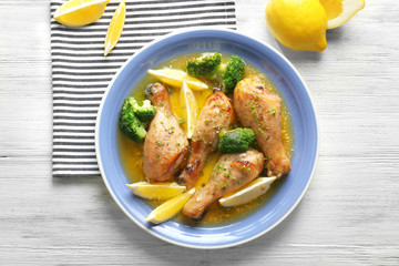 Delicious chicken legs with lemon on plate