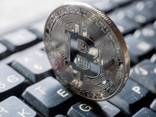 Digital currency physical metal bitcoin coin on the keyboard.