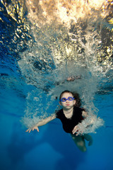 Happy little girl swimming and playing underwater in the bubbles on a blue background. Portrait. Shooting under water. Landscape orientation