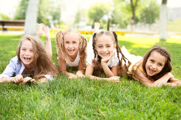 little girls of the girlfriend laying on grass and Having Fun outdoors in summer