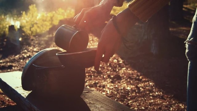 Female hiker serves hot meal from the cauldron