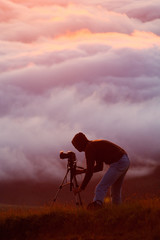 Naklejka premium Photographer shooting natural phenomenon - the clouds that roam the mountains. Concept theme: nature, weather, tourism, extreme, healthy lifestyle, adventures. Unrecognizable persones.