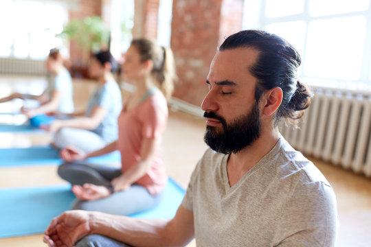 man with group of people meditating at yoga studio