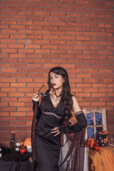 sexy girl in costume of witch.Halloween decorations with spiders and pumpkin bucket for trick or treat. Greeting Card.Halloween pumpkin brick background.Happy Halloween postcard. Ideas for Halloween. 