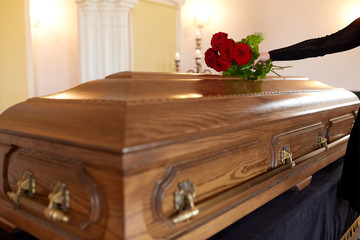 woman with red roses and coffin at funeral
