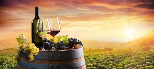 Foto auf Acrylglas Alkohol Flasche und Weingläser auf Fass im Weinberg bei Sonnenuntergang