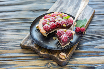 Chunk tartlets with raspberries on a silver fork.