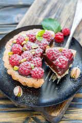 Tartlet with raspberries and fork on the plate.