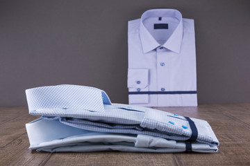 Men's shirts on a wooden table. Folded. The background is gray.