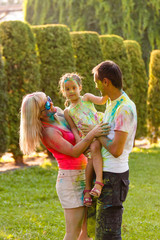 Fototapeta premium Father mother and daughter playing in the park and showering with paints