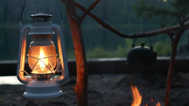 Old fashioned kerosene lamp lantern burning next to the fireplace while camping near the lake