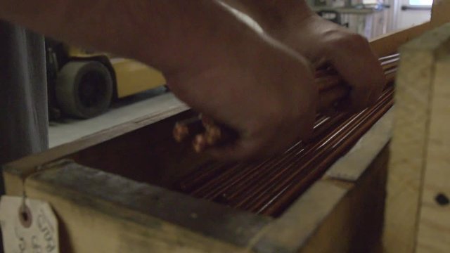 Worker picks up copper rods, close up
