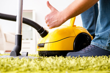 Man cleaning the floor carpet with a vacuum cleaner close up