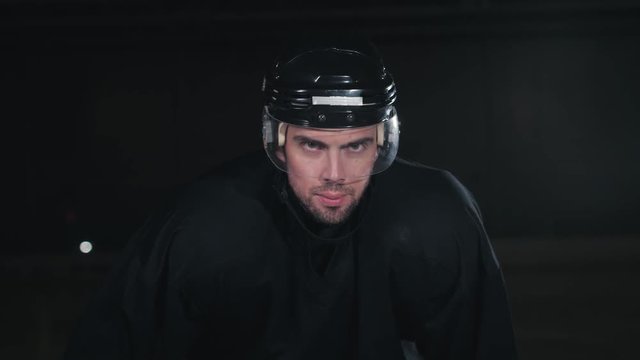 Handsome hockey player. Smiling at camera on dark arena, close up portrait of defender or forward canadian player