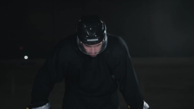 Handsome hockey player. Smiling at camera on dark arena, close up portrait of defender or forward canadian player