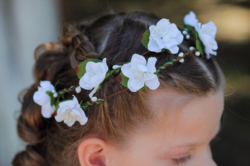 Obraz na płótnie Canvas Wreath of artificial flowers in the hair of a little girl, accessories for hair - wreaths