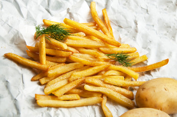 French fries Potatoes and two whole potatoes on a white sheet of paper.
