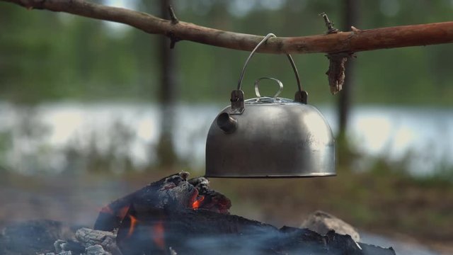Windy camp teapot over fire close-up shot