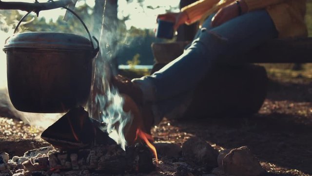 Woman warms herself at camp fire in the forest
