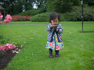 baby girl playing smart phone in garden