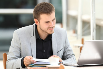 Executive comparing documents on line in a bar