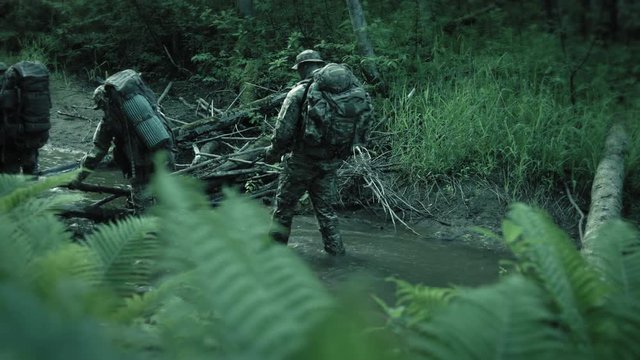 Special forces soldiers crossing obstacles on river