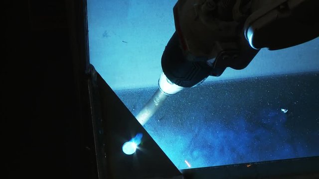 Close up, robot uses welding torch