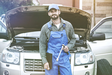 Portrait of auto mechanic working with wrench in engine. Car repair service