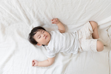 asian baby sleeping on bed