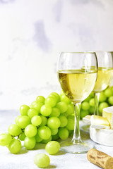 Two glasses of white wine,cheese and grapes.