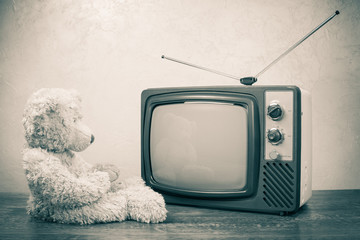 Teddy Bear toy near retro TV. Vintage old style sepia photo