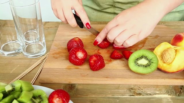 Woman knife regimen of strawberries for fruit salad.  Hd shot with dolly from left to right