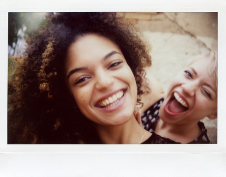 Two girlfriends laughing and looking at camera