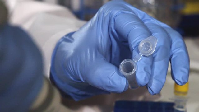 Close up, scientist uses tool to drop liquids in test tube