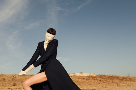 woman wearing coat and covering her face with r turtleneck  sweater at beach