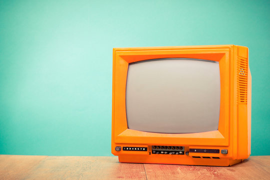Retro old orange TV receiver front turquoise wall background