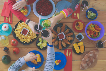 Fototapeta na wymiar Top view of group of people having dinner together while sitting at wooden table. Food on the table. People eat fast food.