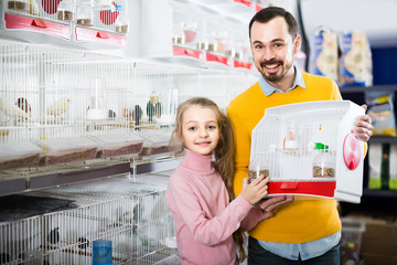 Father and daughter enjoying their purchase of canary bird in pet shop