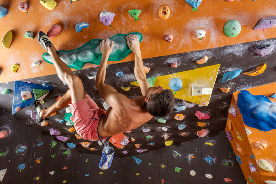 Young man bouldering in indoor climbing gym