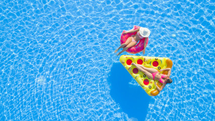 AERIAL TOP DOWN Relaxed girls in pink bikini swimsuits lying on fun inflatable pizza and flamingo...