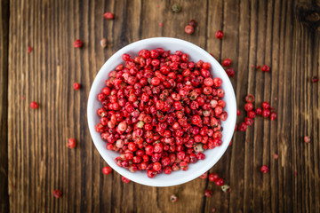 Pink Peppercorns on wooden background; selective focus