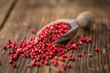 Portion of Pink Peppercorns on wooden background, selective focus