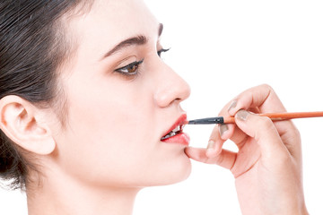 Fototapeta premium Stylist applying red lip gloss to the beautiful woman